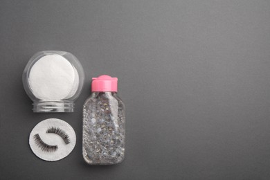 Flat lay composition with makeup remover and false eyelashes on dark grey background. Space for text