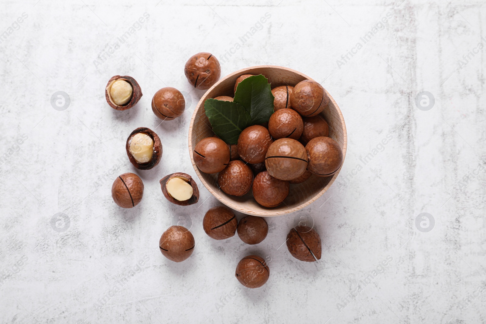 Photo of Delicious organic Macadamia nuts on white textured table, flat lay