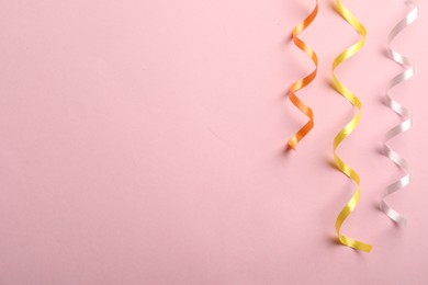 Photo of Colorful serpentine streamers on pink background, flat lay. Space for text