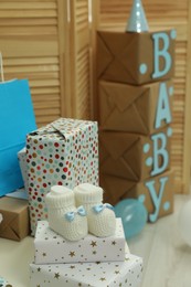 Photo of Baby shower party. Booties, many gift boxes and bags in decorated room