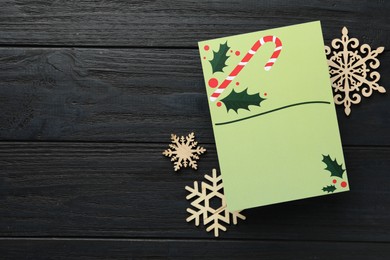 Photo of Blank Christmas invitation card and decorative snowflakes on black wooden table, flat lay. Space for text
