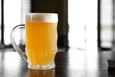 Photo of Glass of tasty beer on wooden table in bar