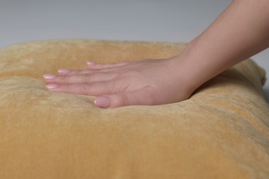 Photo of Woman touching soft yellow pillow on bed, closeup