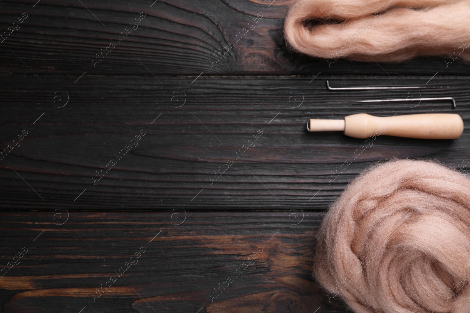 Photo of Beige felting wool and needles on wooden table, flat lay. Space for text