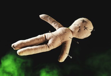 Image of Voodoo doll with pins and smoke on dark background