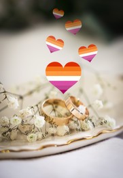 Image of Illustration of hearts in color of lesbian flag, beautiful wedding rings and gypsophila flowers on white cloth, closeup view