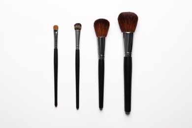 Photo of Different makeup brushes on white background, flat lay