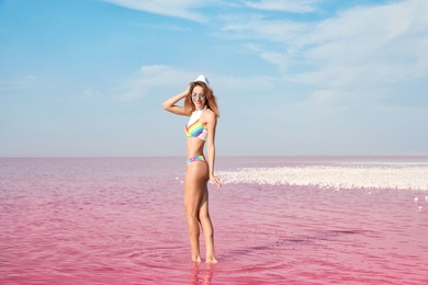 Photo of Beautiful woman posing in pink lake on sunny day