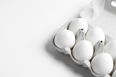 Photo of Fresh chicken eggs in box on white background. Space for text