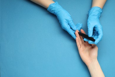 Photo of Diabetes. glucose testing. Doctor using lancet pen on blue background, top view. Space for text
