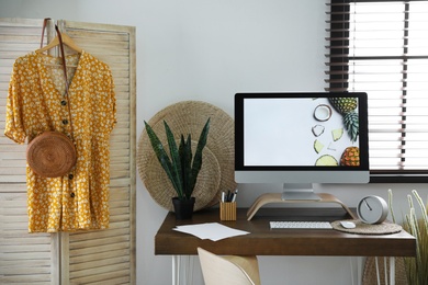 Photo of Comfortable workplace near window with horizontal blinds in room