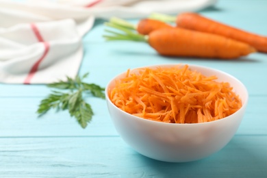 Photo of Bowl of grated carrot on color background. Space for text