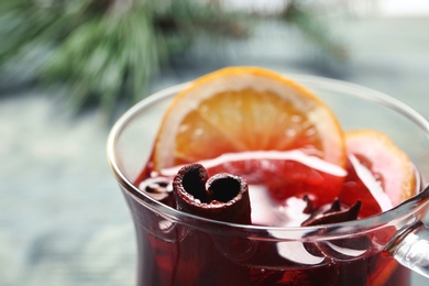 Photo of Cup with red mulled wine against blurred background, closeup