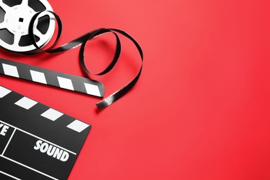 Photo of Clapboard and reel on red background, flat lay with space for text. Video production equipment