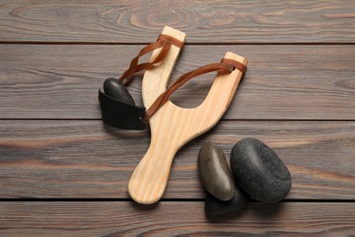 Photo of Slingshot with stones on wooden background, flat lay