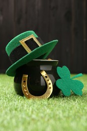 Photo of St. Patrick's day. Pot of gold with leprechaun hat, horseshoe and decorative clover leaf on green grass