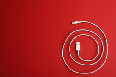 Photo of USB charge cable on red background, top view. Space for text