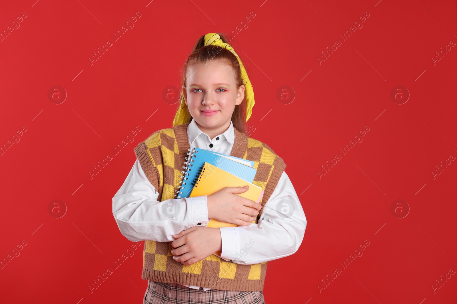 Photo of Cute indie girl with books on red background