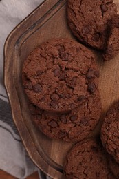 Photo of Board with tasty chocolate cookies on beige tablecloth, top view