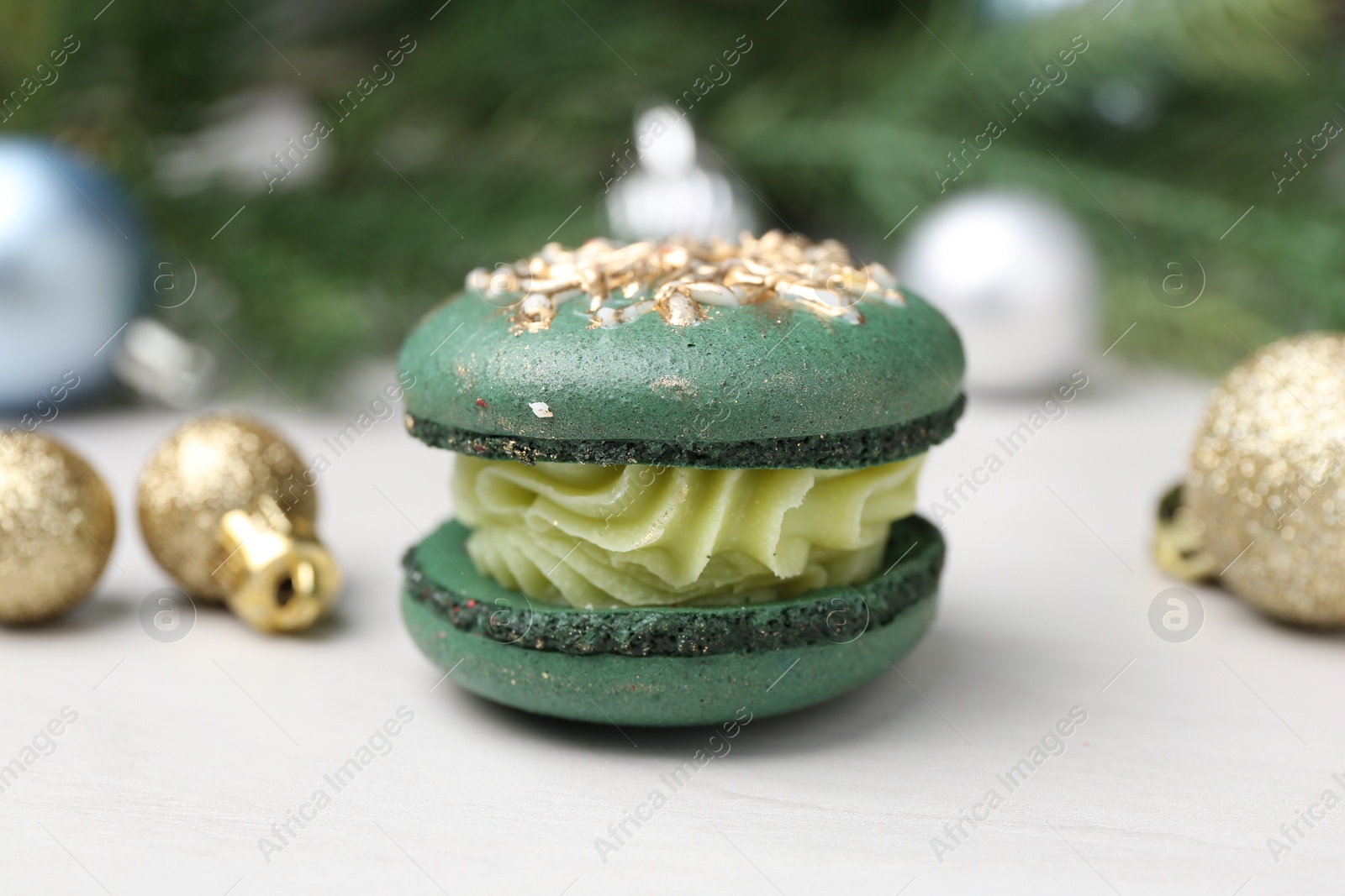 Photo of Decorated Christmas macaron and festive decor on white table, closeup