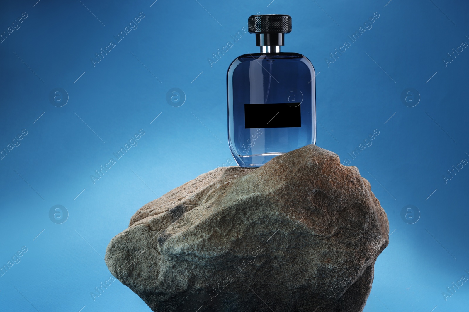 Photo of Stylish presentation of luxury men`s perfume on stone against light blue background. Space for text