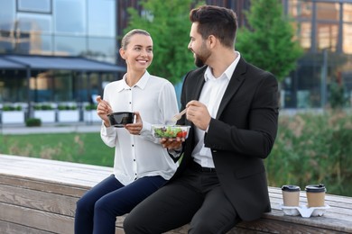 Photo of Business people eating from lunch boxes outdoors
