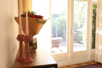 Photo of Bouquet of flowers and candles on wooden table indoors. Space for text