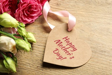 Image of Happy Mother's Day. Heart shaped greeting label and beautiful flowers on wooden table