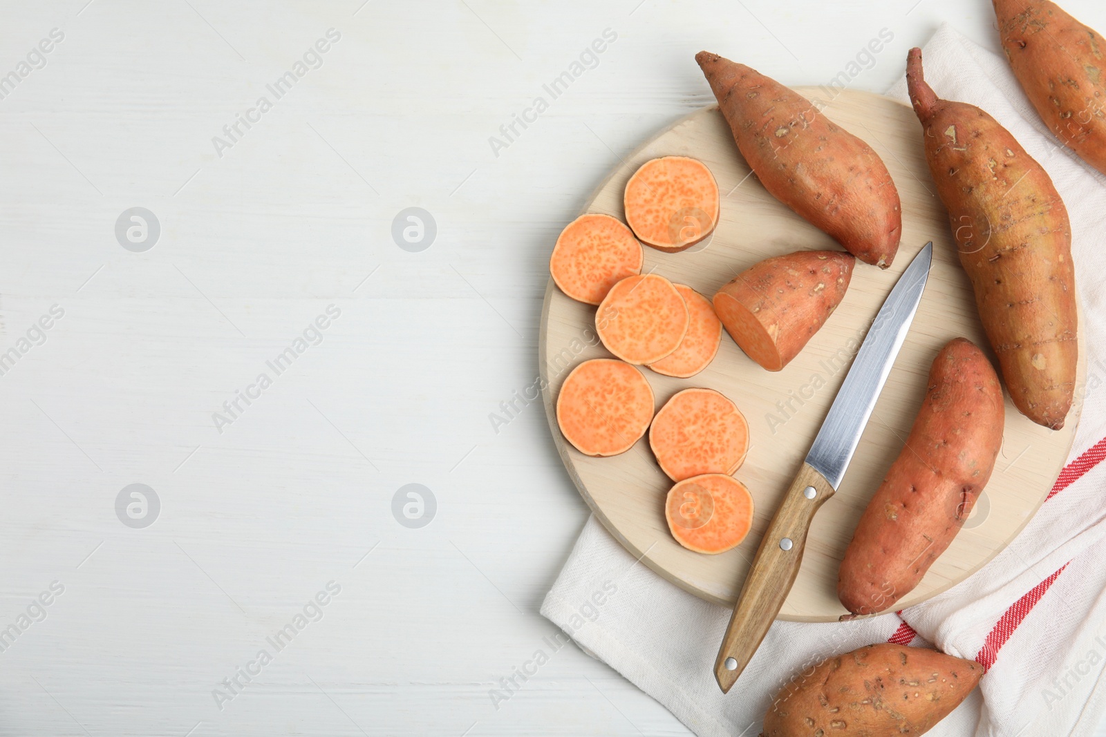 Photo of Whole and cut ripe sweet potatoes on white wooden table, flat lay. Space for text