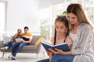 Photo of Mother reading book with child at home. Happy family