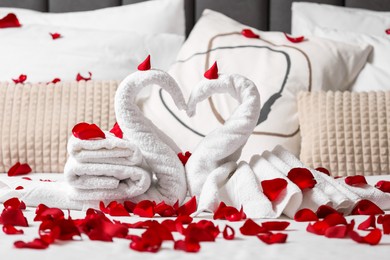 Photo of Honeymoon. Swans made with towels and beautiful rose petals on bed