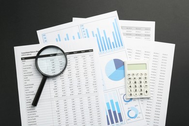 Photo of Accounting documents, calculator and magnifying glass on black table, top view