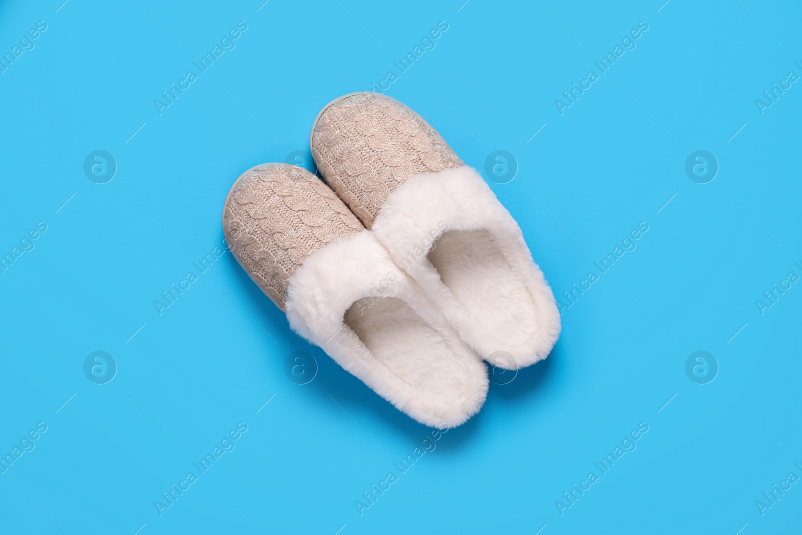 Pair of beautiful soft slippers on light blue background, top view Photo of Pair of beautiful soft slippers on light blue background, top view