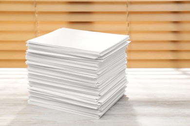Photo of Stack of paper sheets on white wooden table