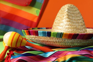 Photo of Composition with Mexican sombrero hat, poncho and maracas on table, closeup