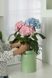 Photo of Woman making bouquet of beautiful hortensia flowers in kitchen, closeup