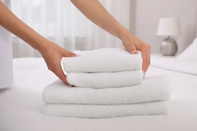 Photo of Chambermaid putting fresh towels on bed in hotel room, closeup