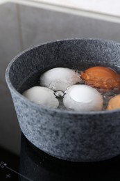 Photo of Chicken eggs boiling in saucepan on electric stove, closeup