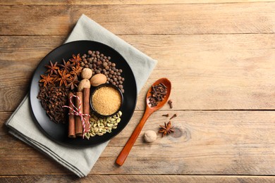 Dishware with different spices on wooden table, flat lay. Space for text