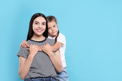 Photo of Happy woman with her cute daughter on light blue background, space for text. Mother's day celebration