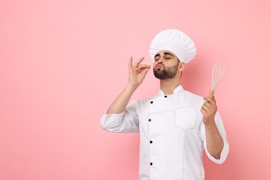 Photo of Professional chef holding whisk and showing perfect sign on pink background. Space for text