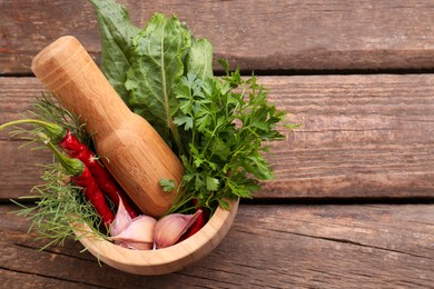 Photo of Mortar with pestle and different ingredients on wooden table, top view. Space for text