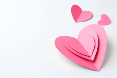 Photo of Pink paper hearts on white background. Space for text