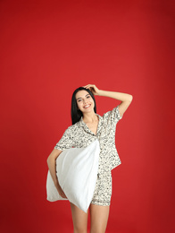 Photo of Young woman with pillow on red background