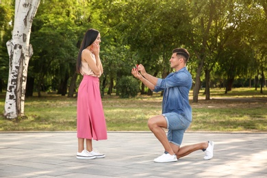 Photo of Man with engagement ring making proposal to his girlfriend in park