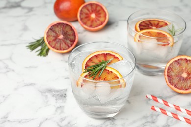 Photo of Delicious refreshing drink with sicilian orange and rosemary on white marble table