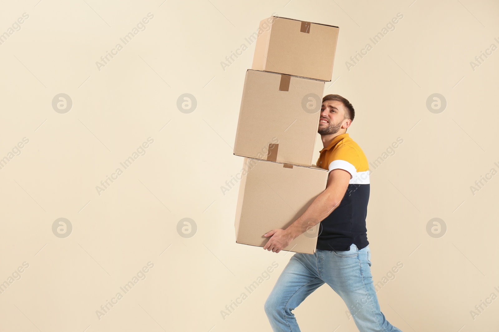 Photo of Portrait of young man carrying carton boxes on color background. Posture concept