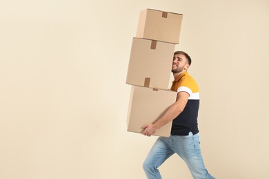 Photo of Portrait of young man carrying carton boxes on color background. Posture concept