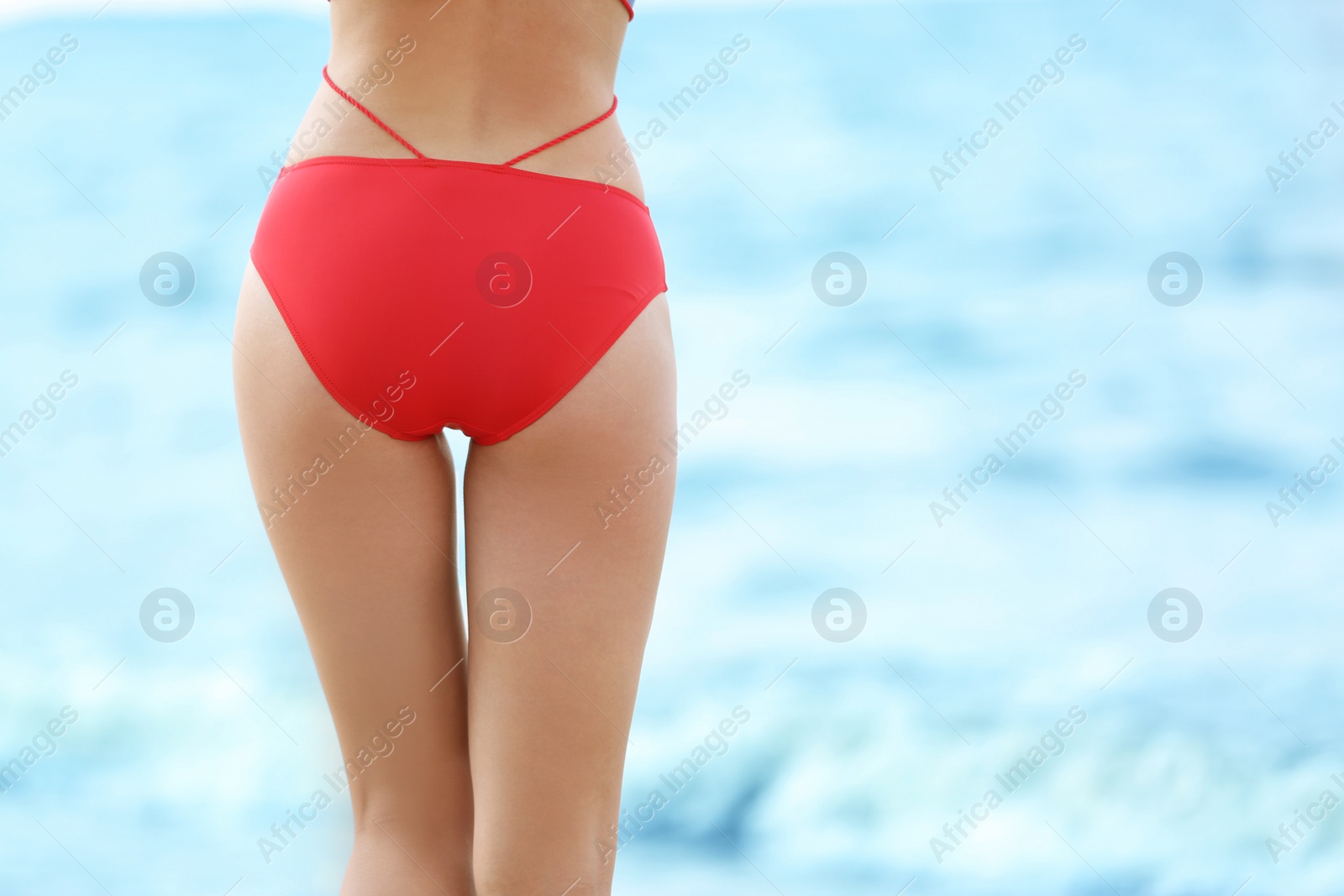 Photo of Attractive young woman in beautiful swimsuit on beach, closeup