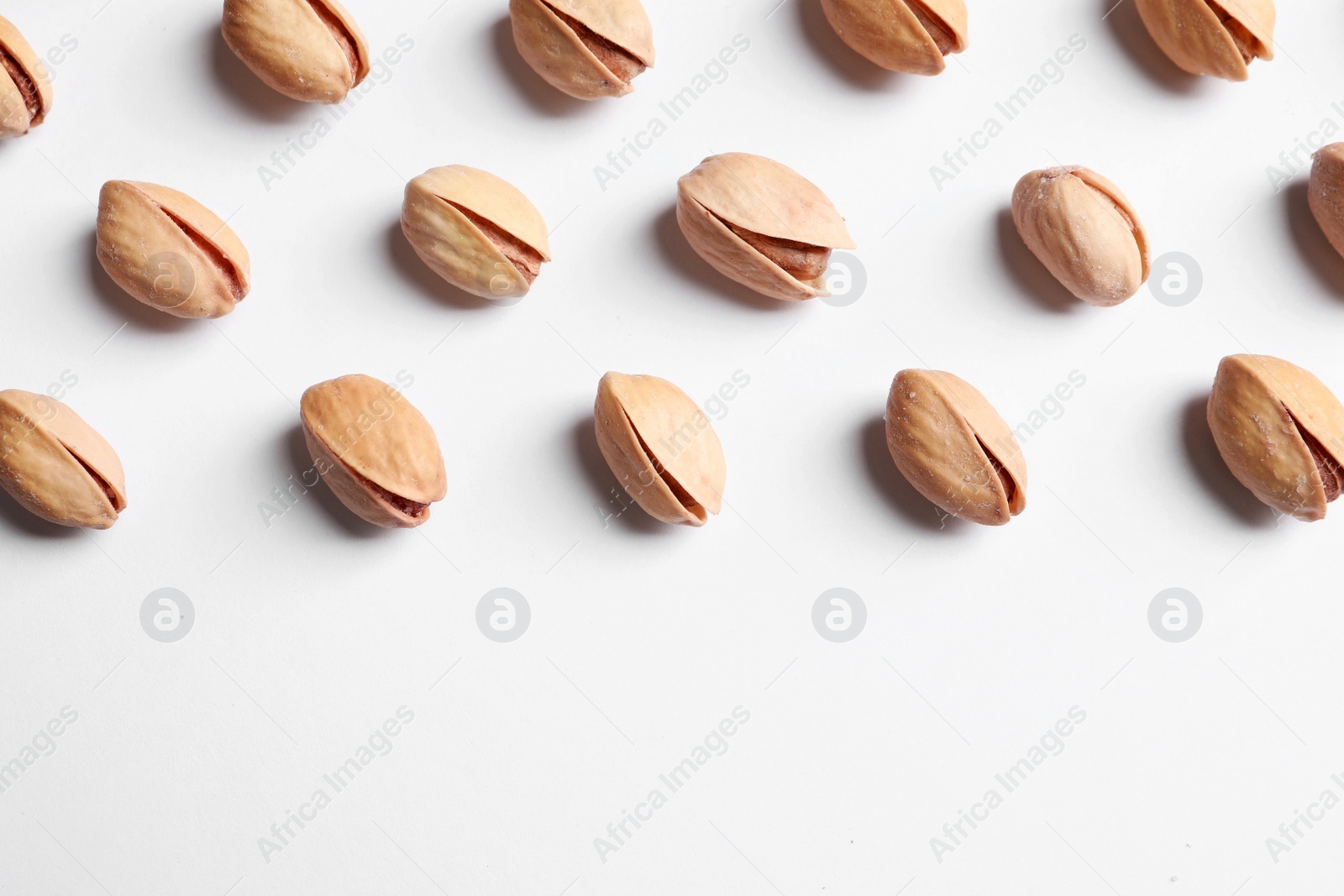 Photo of Organic pistachio nuts on white background, flat lay. Space for text